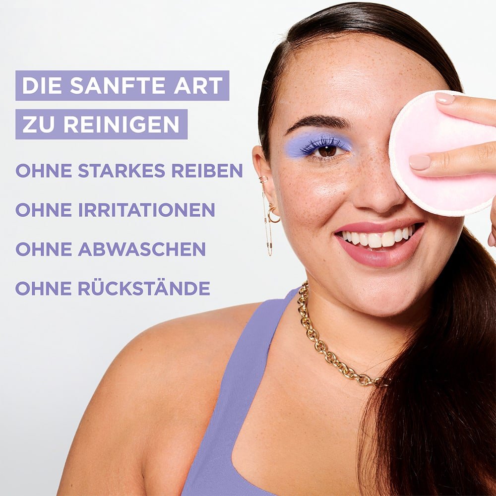 Lächelnde Frau wischt sich mit einem Reinigungspad über das linke Auge